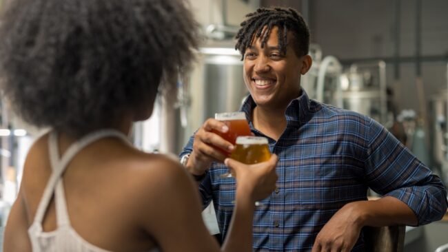 Two people cheersing beers in brewery