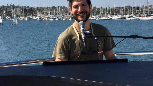 Pianist, vocalist and percussionist Jonny Greco smiling near Bay Area water